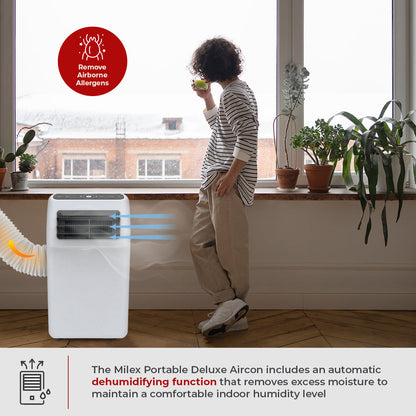 Young man standing by a window with a Milex portable air conditioner in the foreground, featuring text about its dehumidifying function.