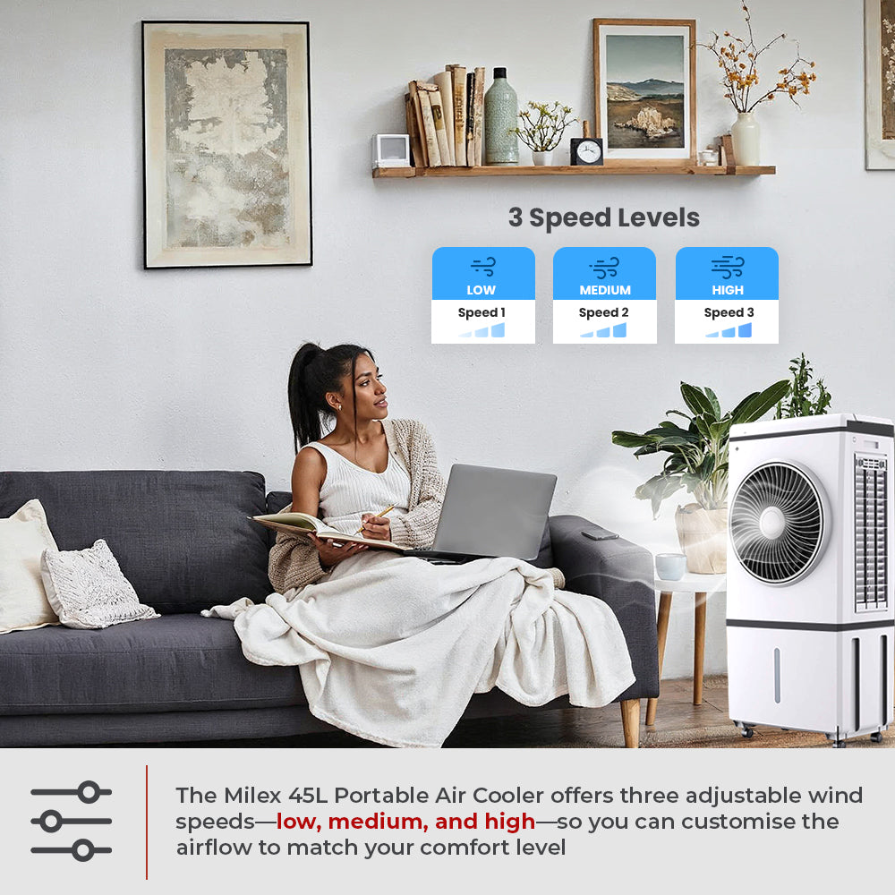 Woman sitting on a couch using a laptop with a portable Milex 45L Portable Air Cooler in the room.